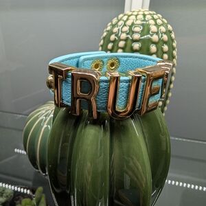 Blue Leather Adjustable Bracelet with Gold Letters Spelling True.